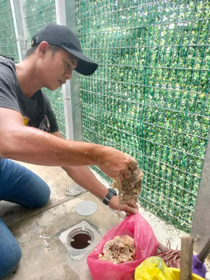 Imej tukang sedang membaiki lubang saluran lantai yang tersumbat dengan bendasing